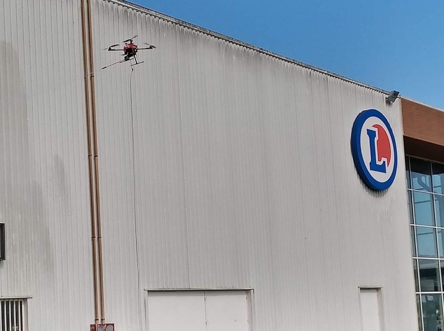 Drone devant une façade de bâtiment commercial en bardage métallique.
